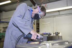 Man in work coveralls working with metal machinery